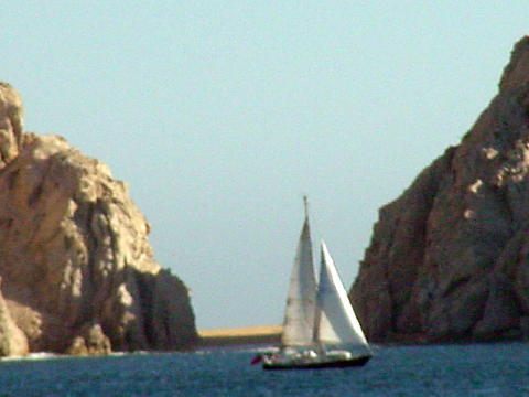 A sail boat crosses in front of Lover's Beach